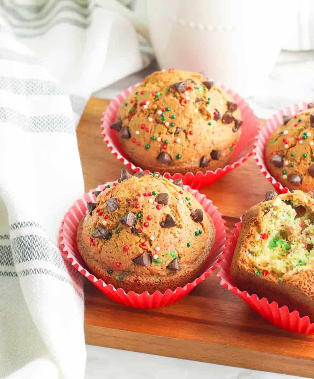 Chocolate chip Christmas muffins served on a wooden cutting board.