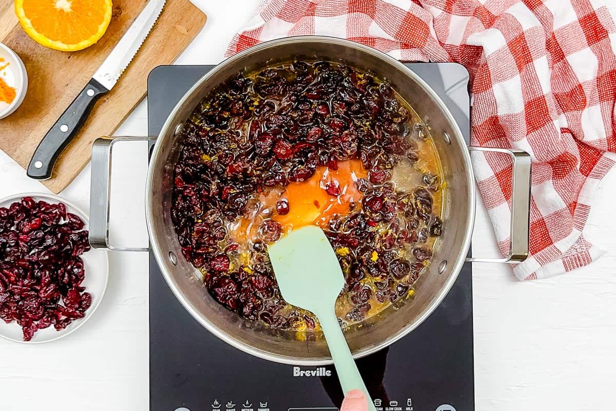 Mixing together the cranberry sauce in a large metal pot.