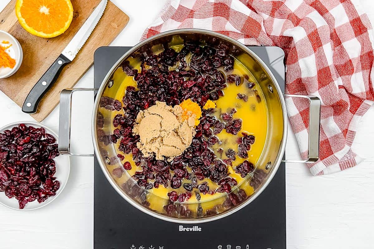 Adding the ingredients for the cranberry sauce to a large metal pot.