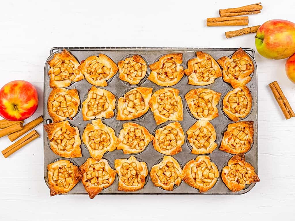 Crispy and golden baked mini apple pies in the ،in tray.