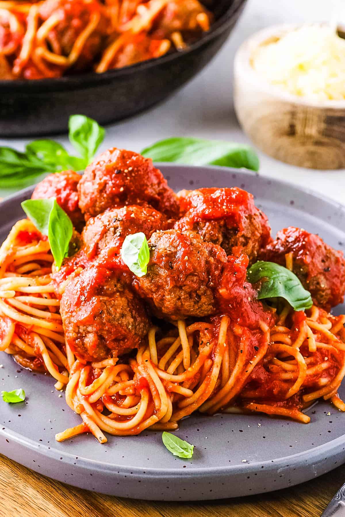 Easy tofu meatballs, tossed with marinara sauce and served on top of pasta, on a grey plate.