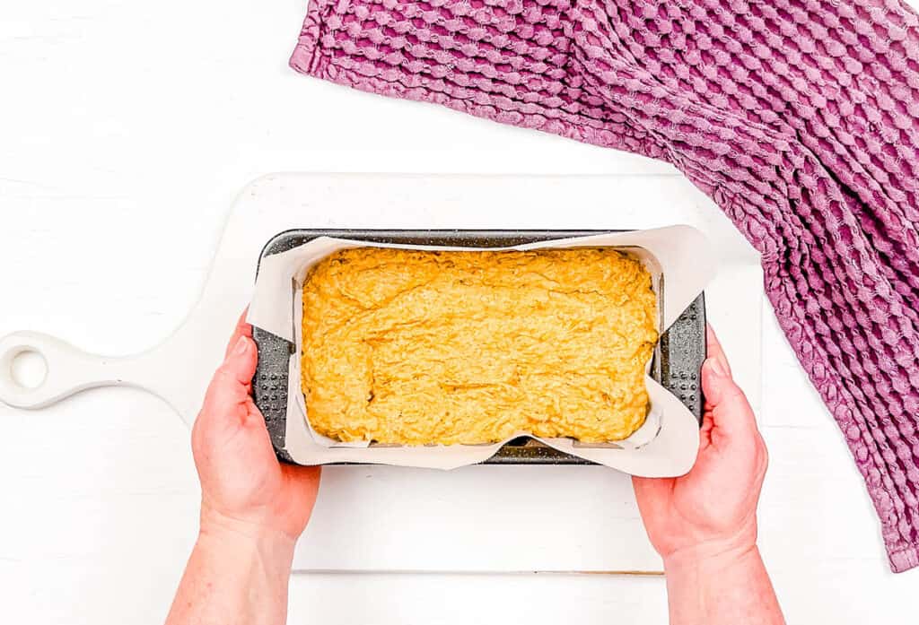 Banana pumpkin bread batter added to loaf pan lined with parchment paper.