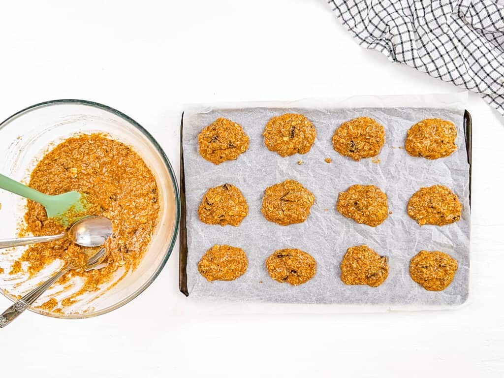 Gluten free ،feeding cookie dough scooped out onto a baking sheet lined with parchment paper.