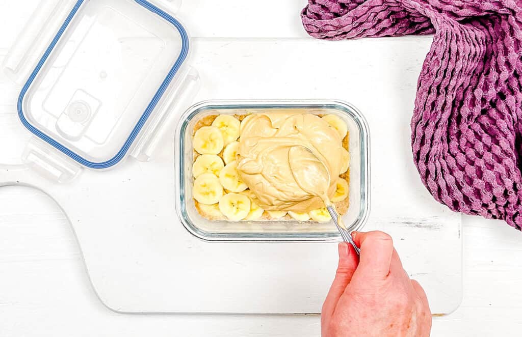 Sliced bananas topped with yogurt in a glass container.