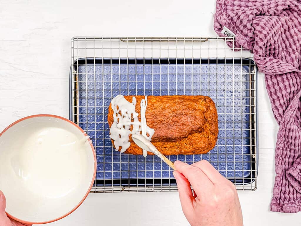 Vanilla glaze added to quick bread on a wire rack.