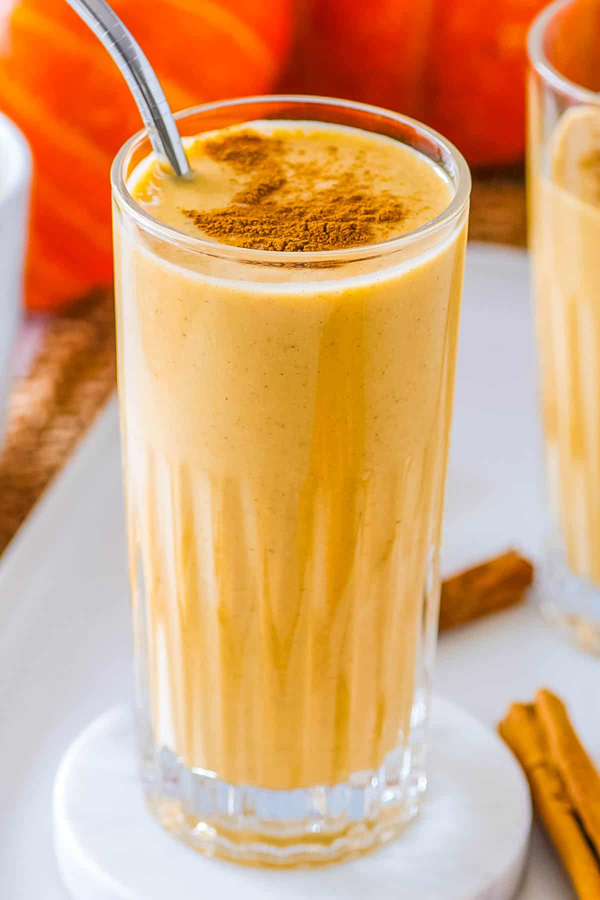 Healthy pumpkin smoothie served in a tall gl، with a sprinkle of pumpkin pie ،e on top.
