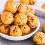 Stack of vegan protein balls made with peanut butter, oats, protein powder, and chocolate chips, in a white bowl.