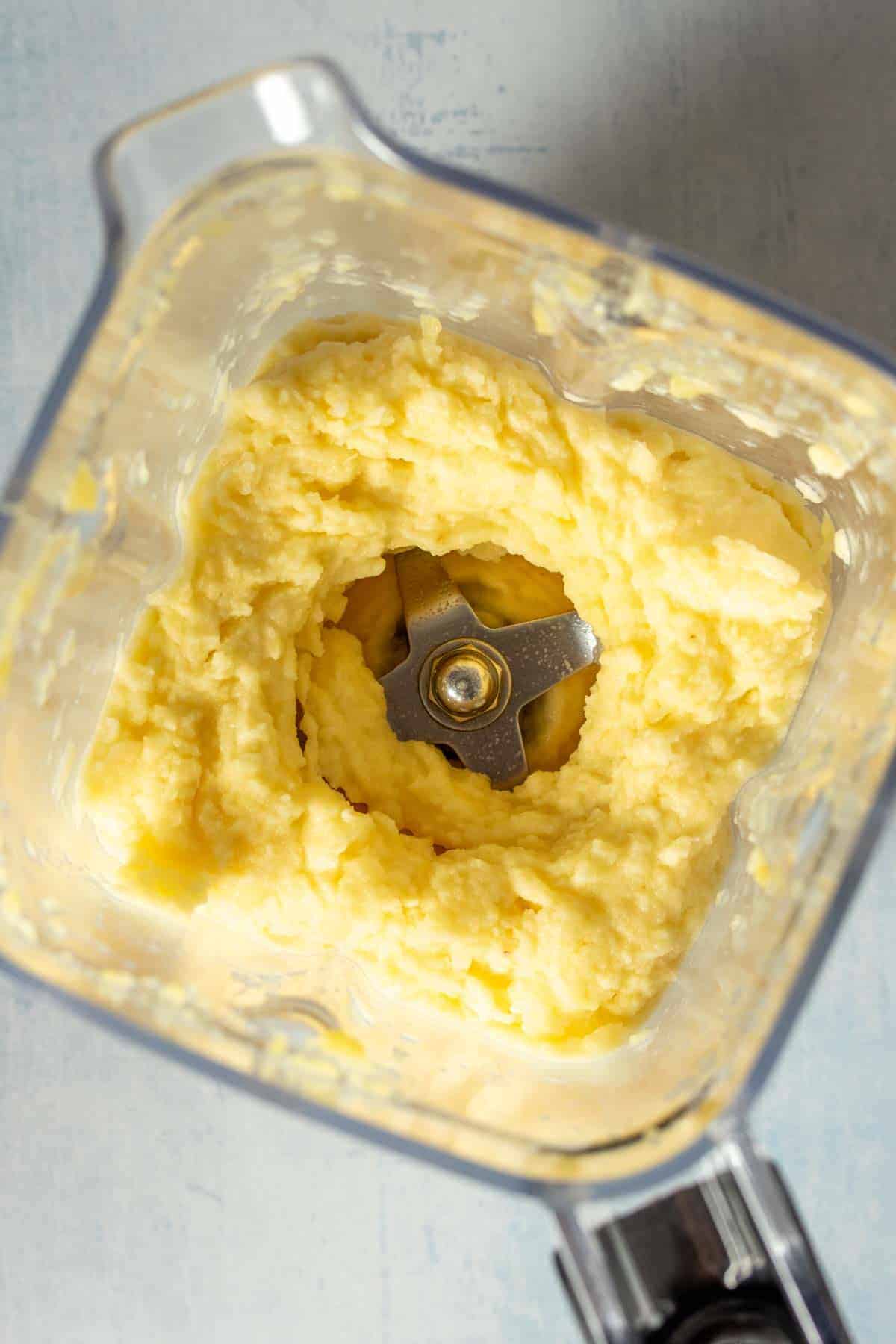 Top view looking into a blender with creamy blended pineapple.
