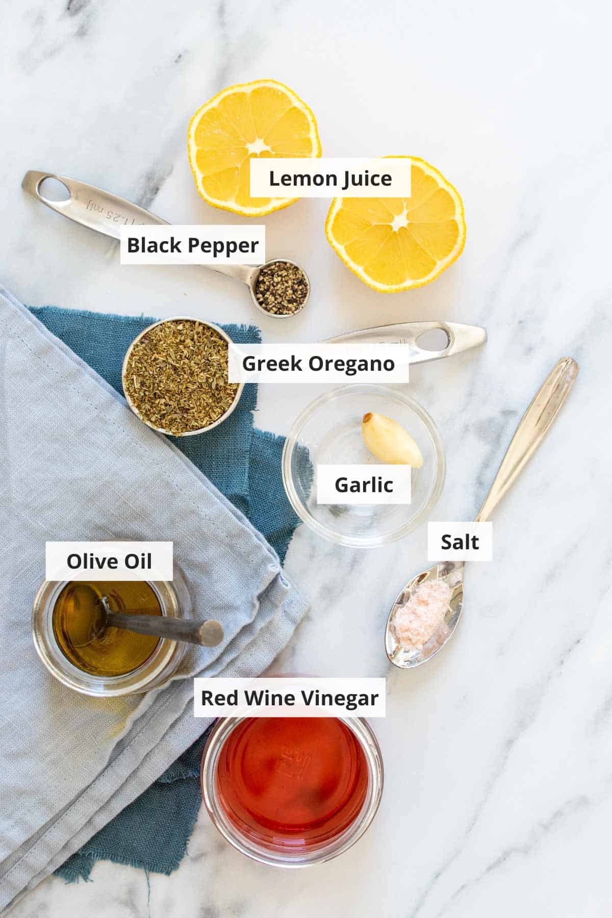 Ingredients for Greek salad dressing on a marble countertop.