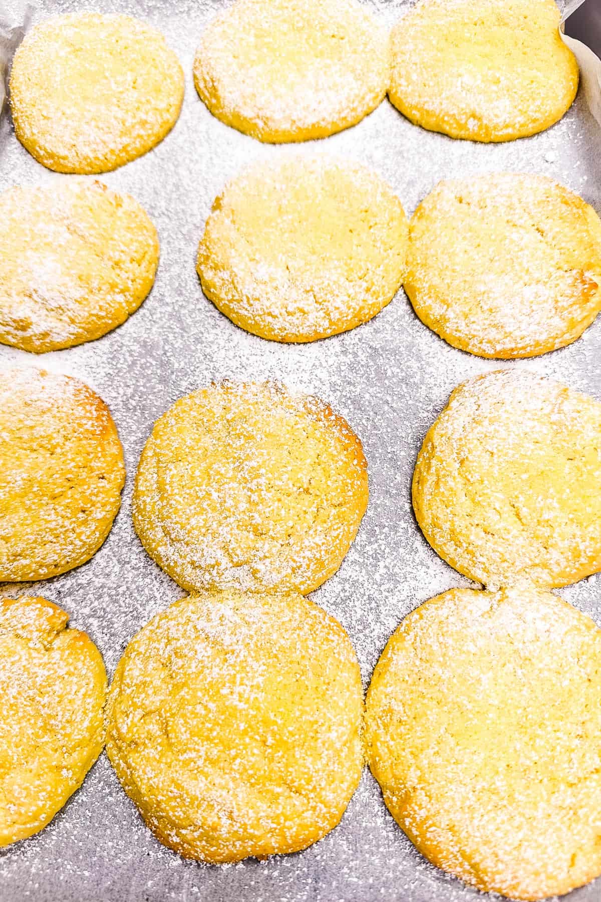 Lemon biscuits cooling after being baked on a baking sheet.