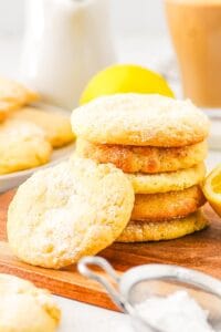 A stack of lemon biscuits with one biscuit leaning on the stack from the side, on a wooden board.