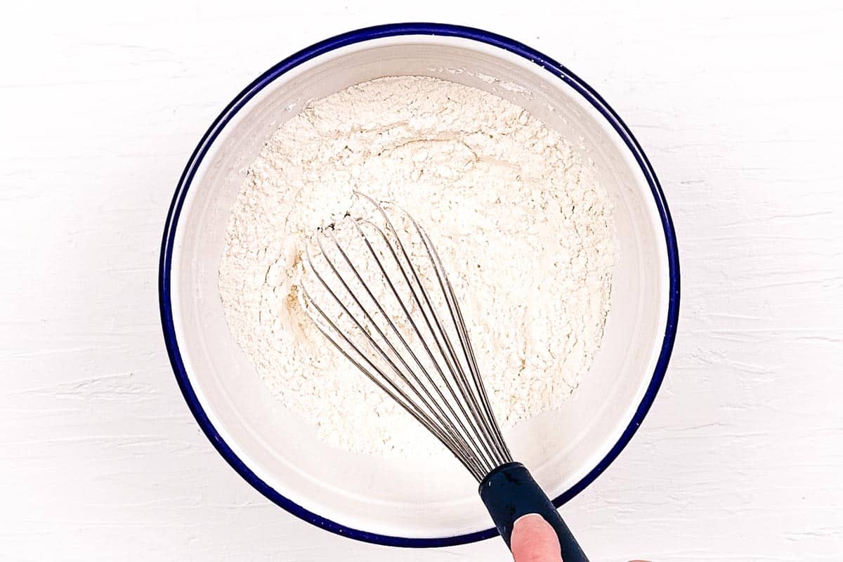 A whisk mixing together the dry ingredients for the lemon biscuits.