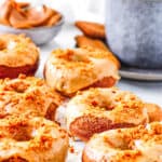 Lotus Biscoff donuts with a cookie butter glaze, stacked on a white piece of parchment paper