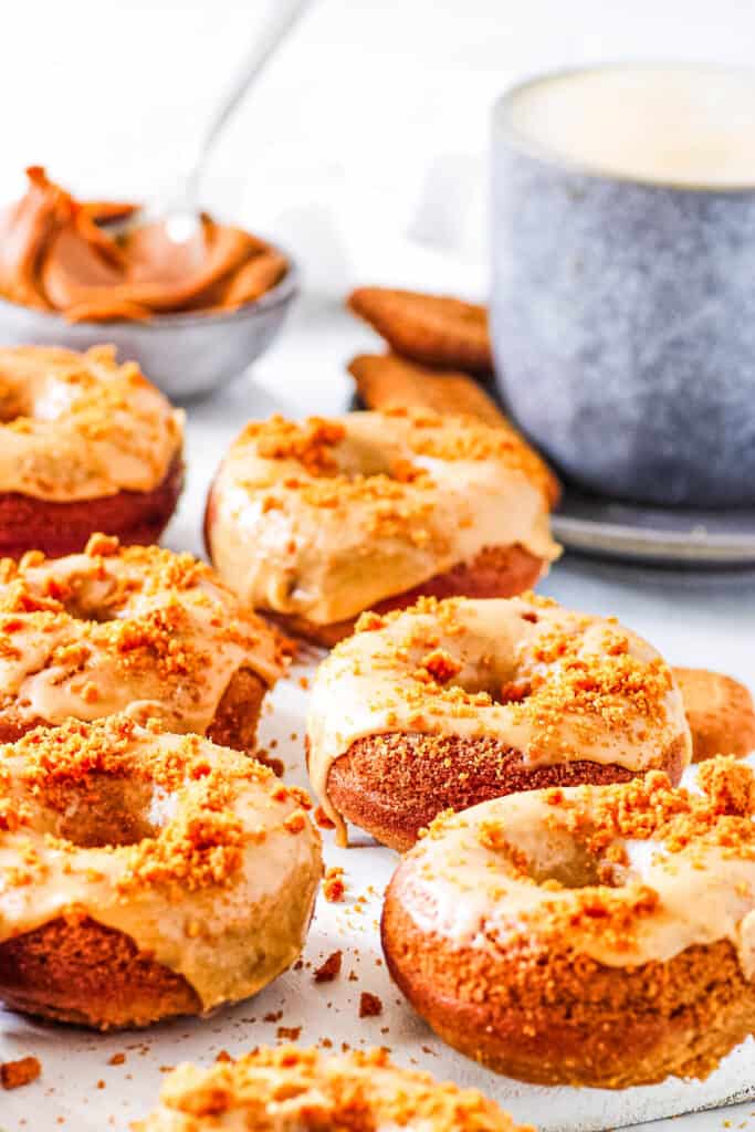 Lotus Biscoff donuts with a cookie butter glaze, stacked on a white piece of parchment paper