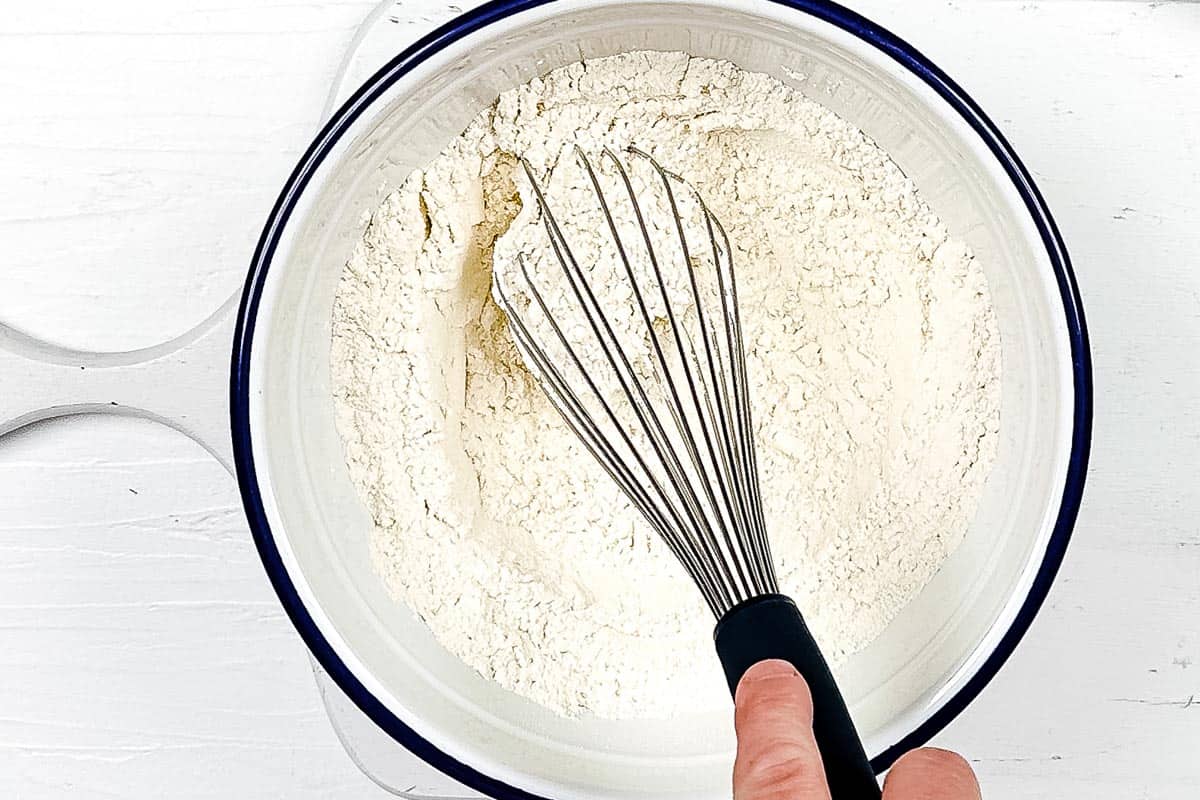 Whisk mixing the dry ingredients for the healthy biscuits together in a large mixing bowl. 