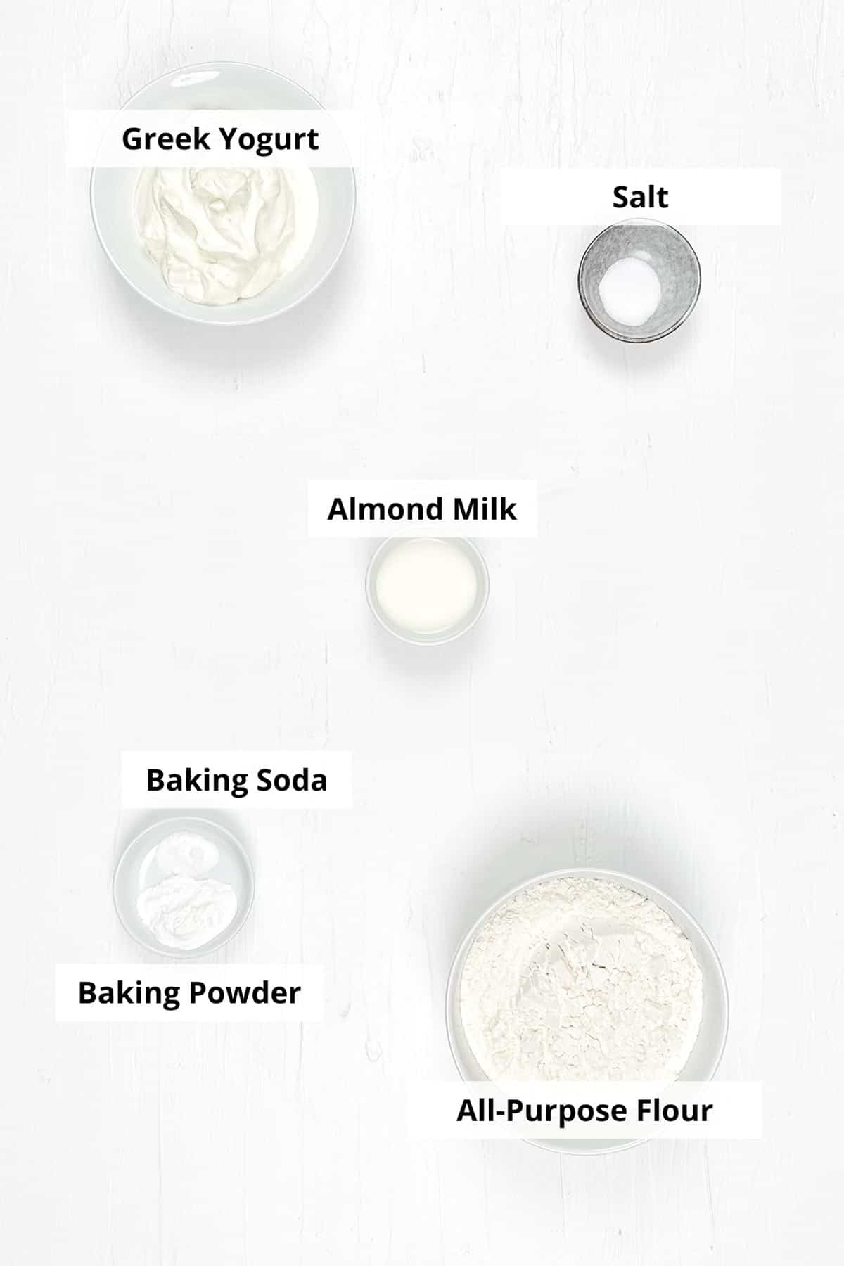 Ingredients for low calorie biscuits laid out in ceramic bowls, on a white background. 