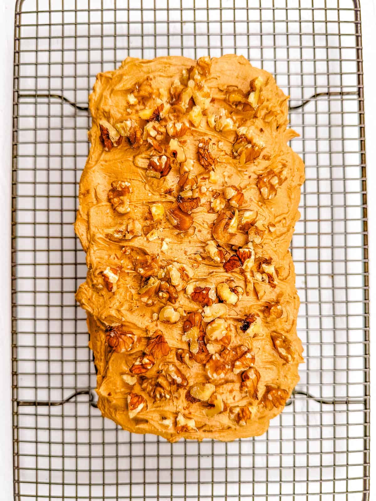 Walnut coffee cake iced with coffee frosting, cooling on a wire rack.