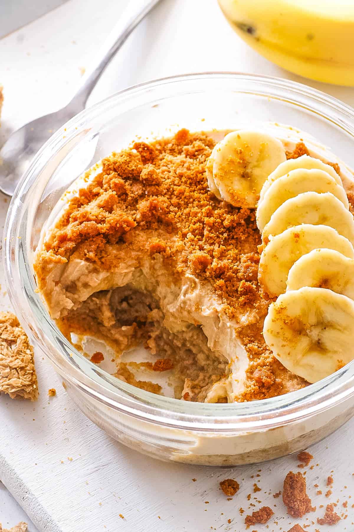 Healthy overnight Weetabix, topped with sliced bananas, served in a gl، bowl.