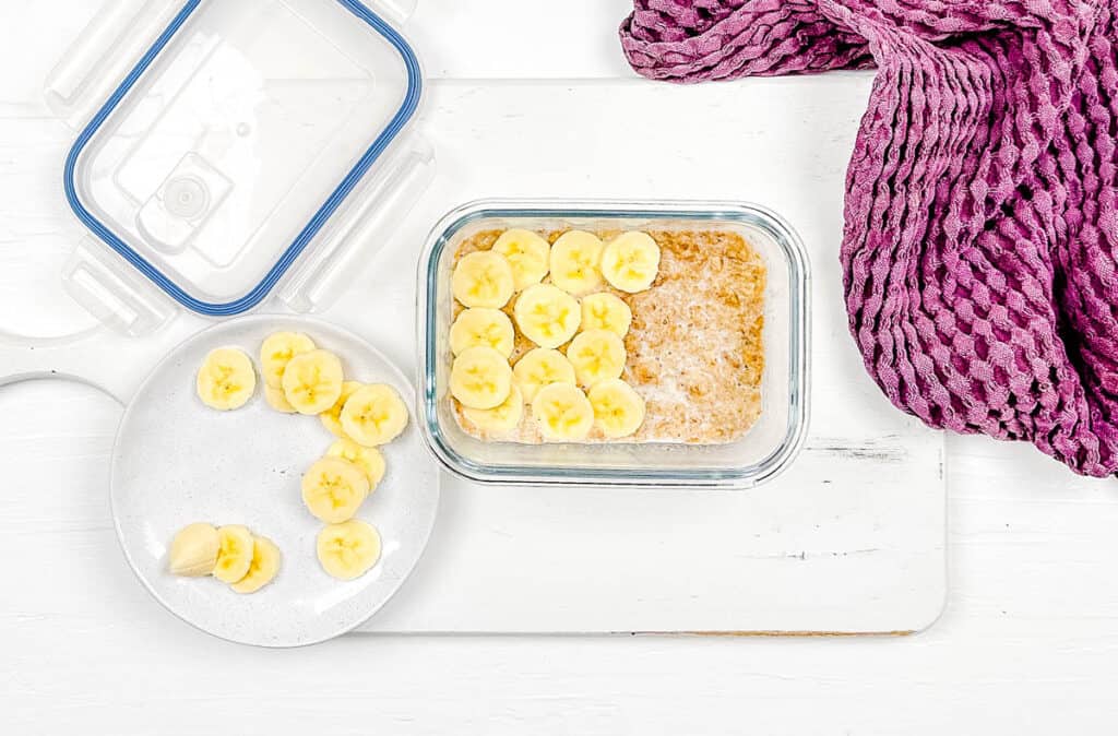 Sliced bananas layered with yogurt in a glass container.