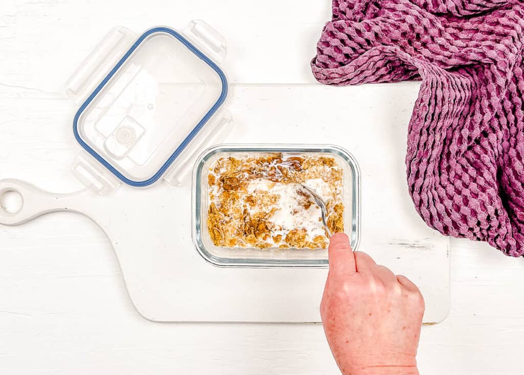 Weetabix and milk mixed in a glass container.