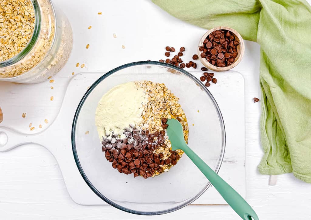 Oats, protein powder and chocolate chips mixed in a mixing bowl.