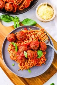 Easy vegan tofu meatballs, tossed with marinara sauce and served on top of pasta, on a grey plate.