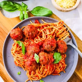 Easy vegan tofu meatballs, tossed with marinara sauce and served on top of pasta, on a grey plate.