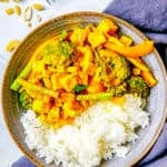 Thai tofu yellow curry with broccoli, potatoes, asparagus and peppers served in a grey bowl.