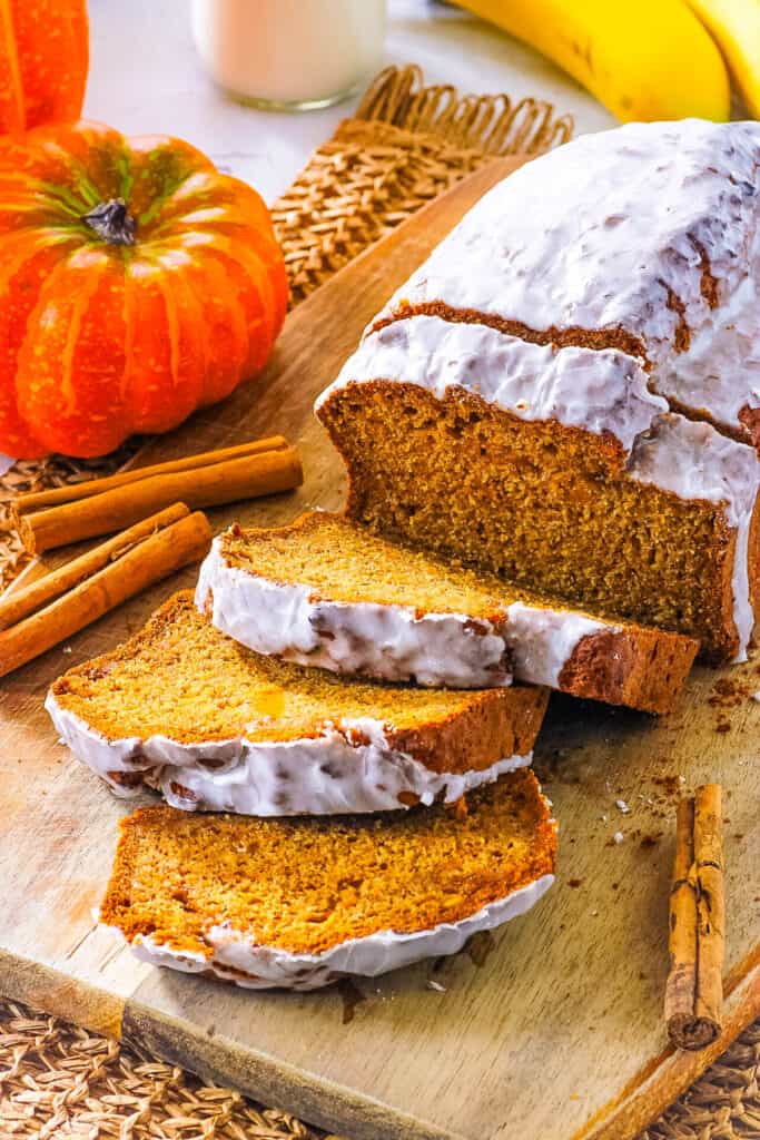 Vegan pumpkin banana bread, sliced on a wooden cutting board.