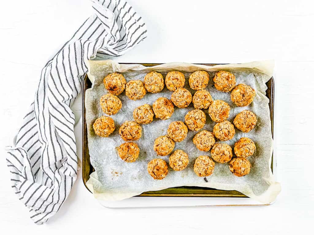 Baked vegan tofu meatballs on a baking sheet lined with parchment paper.