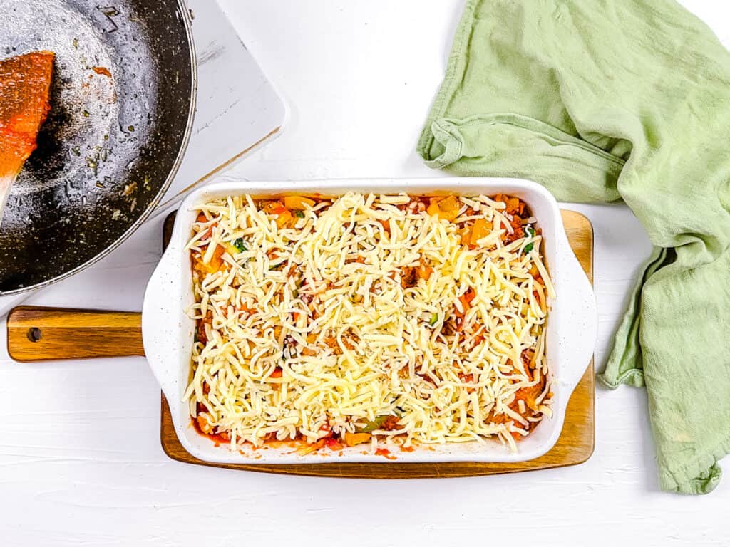 Gluten free squash casserole topped with cheese in a casserole dish.