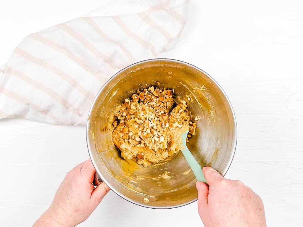 Walnuts mixed into cake batter in a mixing bowl.