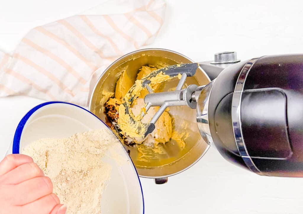 Dry ingredients poured into the bowl of a stand mixer to combine with wet ingredients for cake batter.
