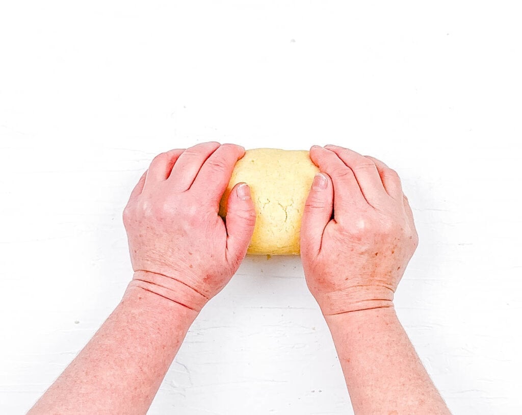 Pie dough being kneaded on a floured surface.