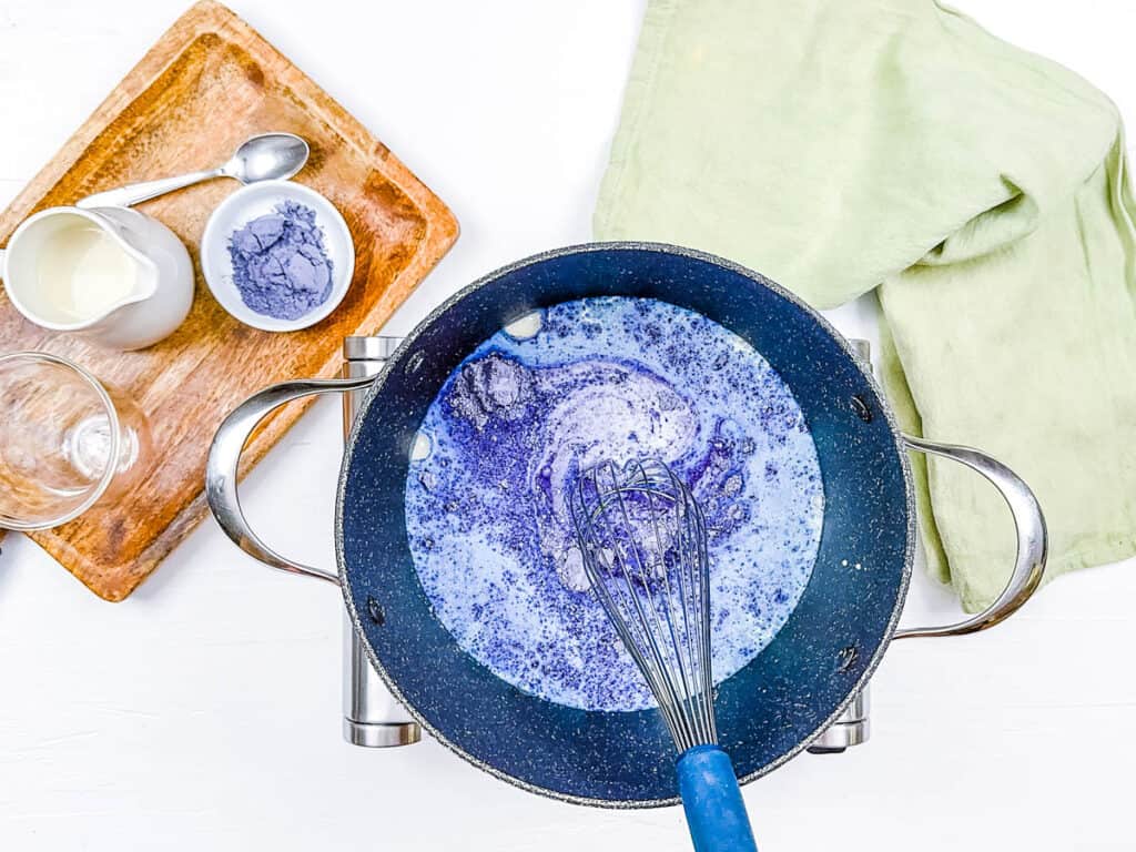 Butterfly pea flower latte cooking in a pot on the stove.