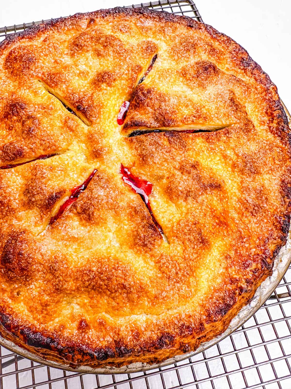 Baked blueberry strawberry pie cooling on a wire rack.