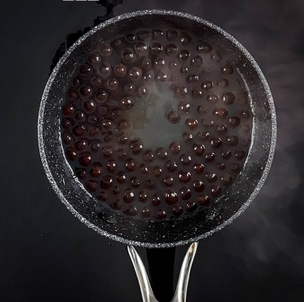 Tapioca pearls cooking in a pot on the stove.