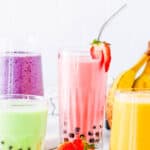 Boba smoothie with four different flavors (strawberry banana, mango, honeydew, and blueberry) served on a white countertop.