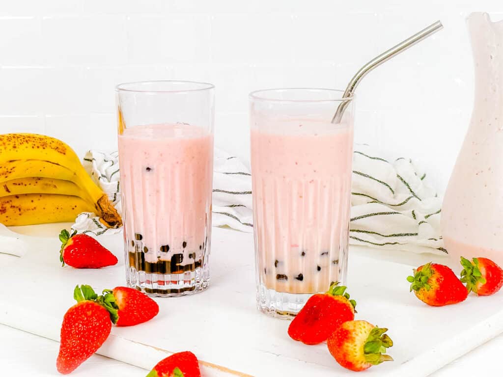 Strawberry banana boba tea smoothie served in glasses with straws.