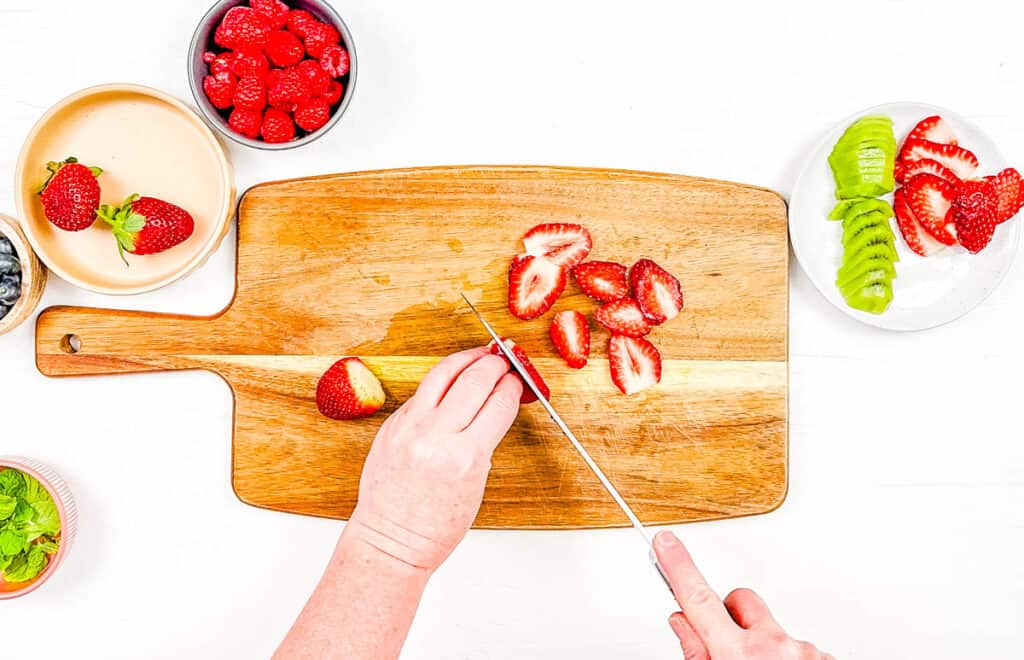 Strawberries cut on a cutting board.