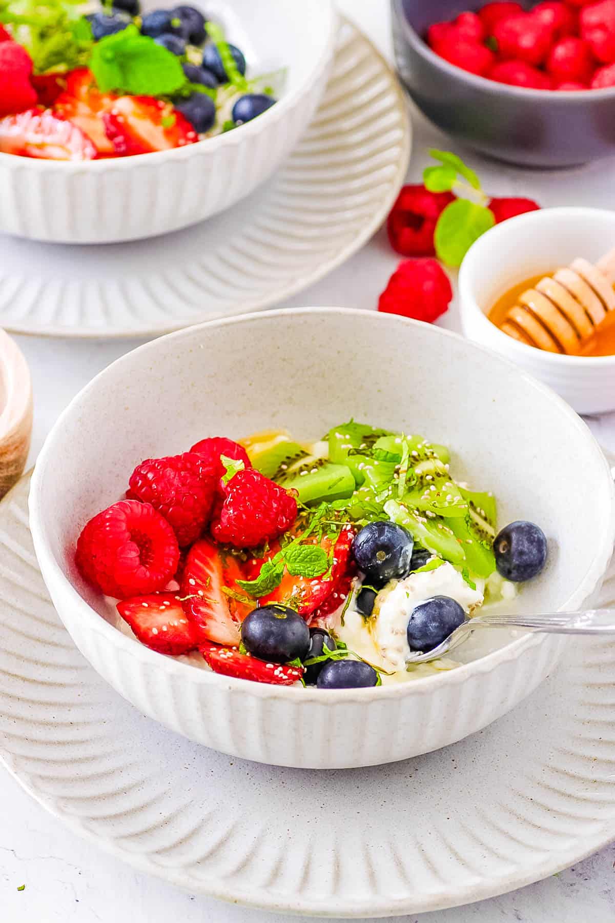 Cottage cheese breakfast bowl with fruit served in a white bowl with a s،.