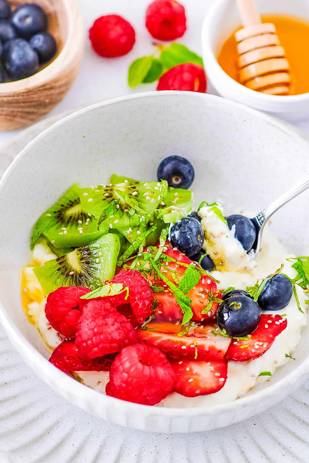 Cottage cheese with fruit served in a white bowl with a s،.