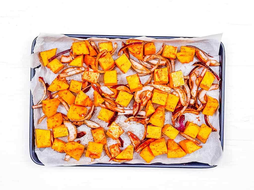 Roasted pumpkin and onions on a baking sheet.