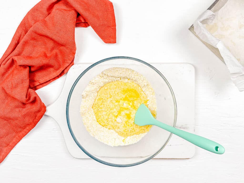 Cornmeal and gluten free flour mixed in a bowl with wet ingredients for gf stuffing.