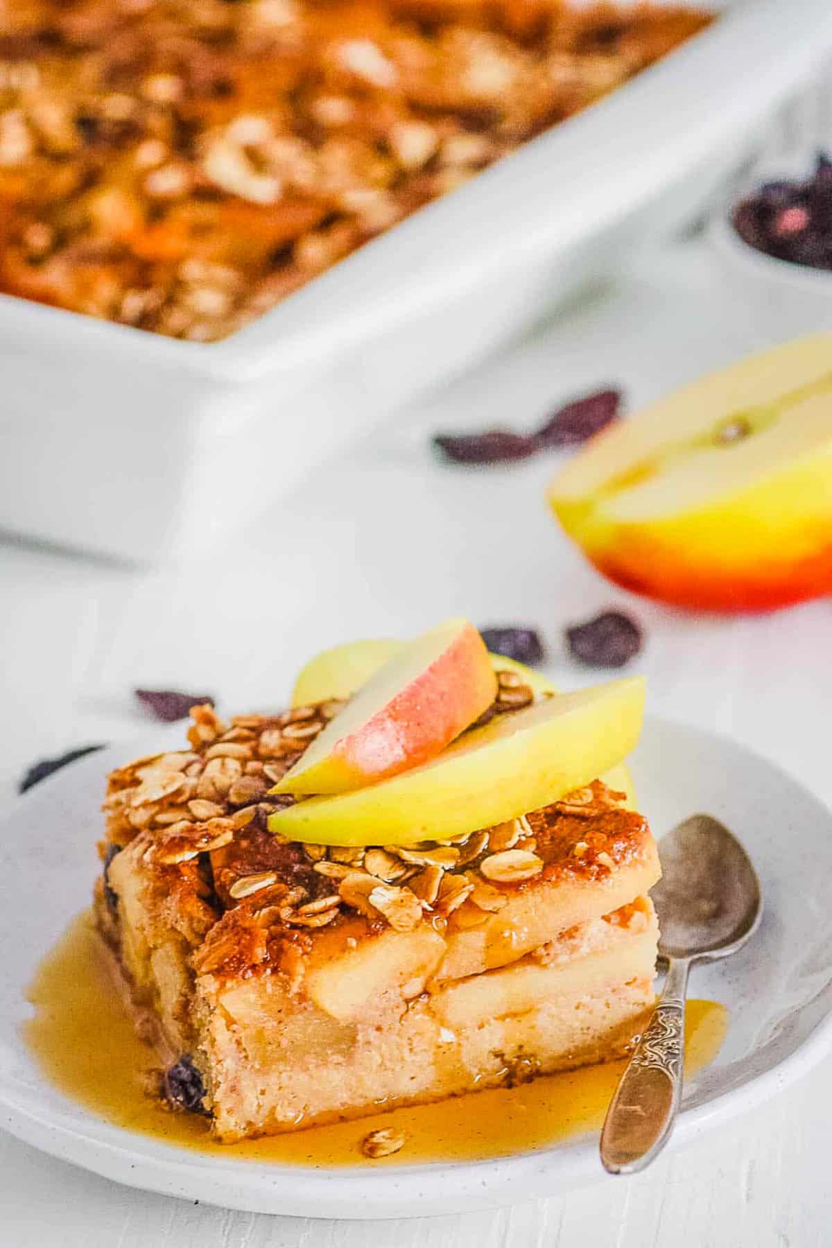 Gluten free apple cake on a plate with maple syrup, garnished with apple slices.