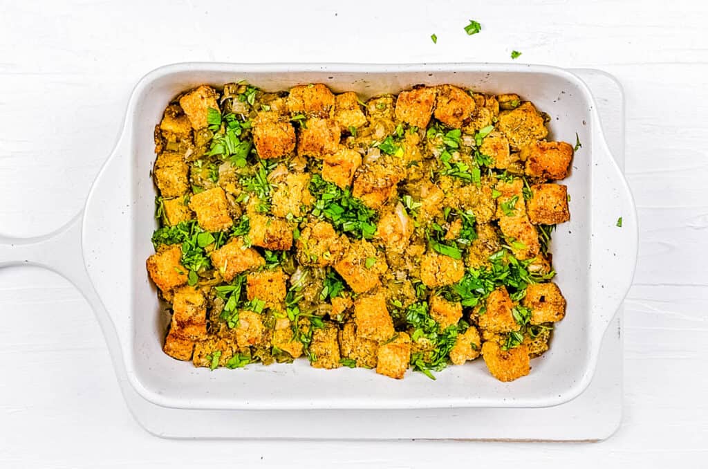 Baked homemade cornbread dressing in a white casserole dish.