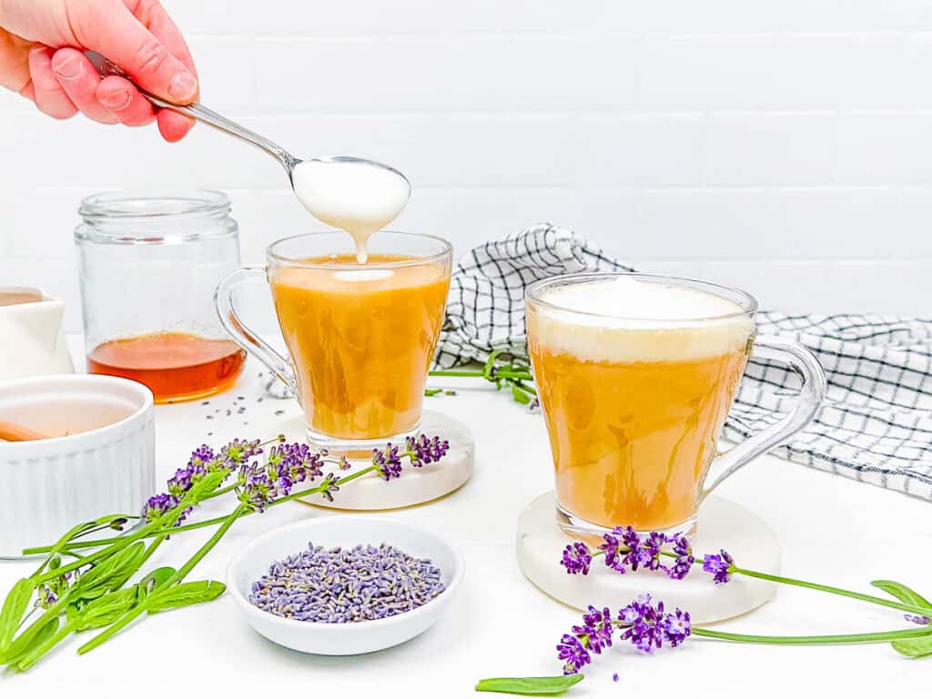 Frothed milk added to lavender coffee in a glass.