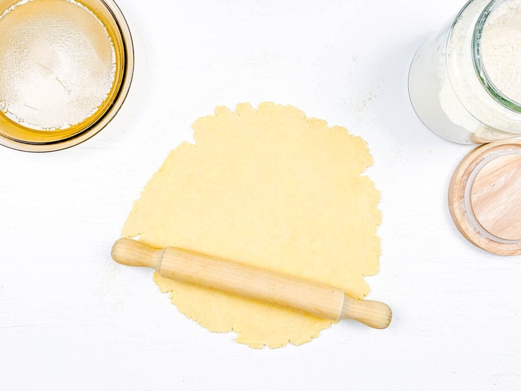 Homemade pie dough being rolled out on a countertop.