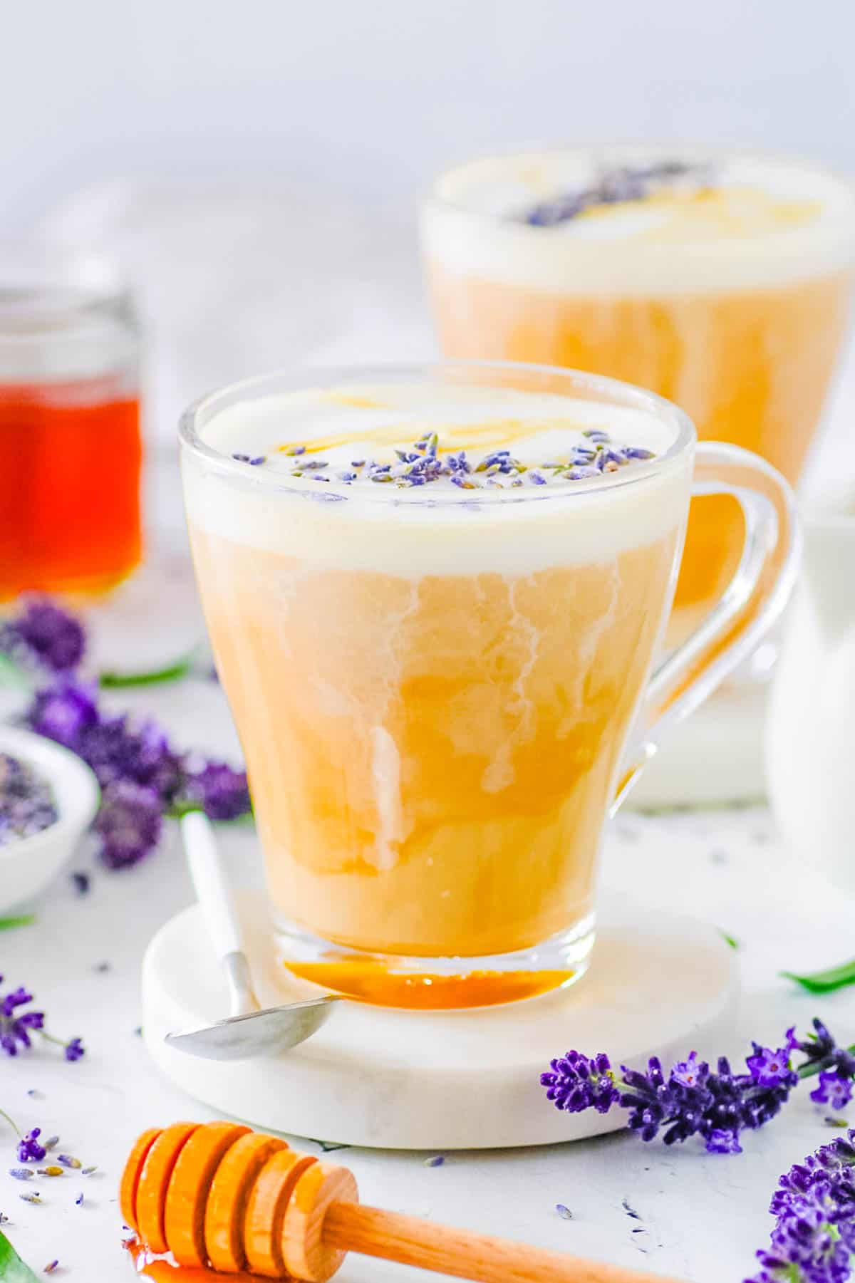 Homemade lavender latte served in a glass, garnished with lavender flowers.