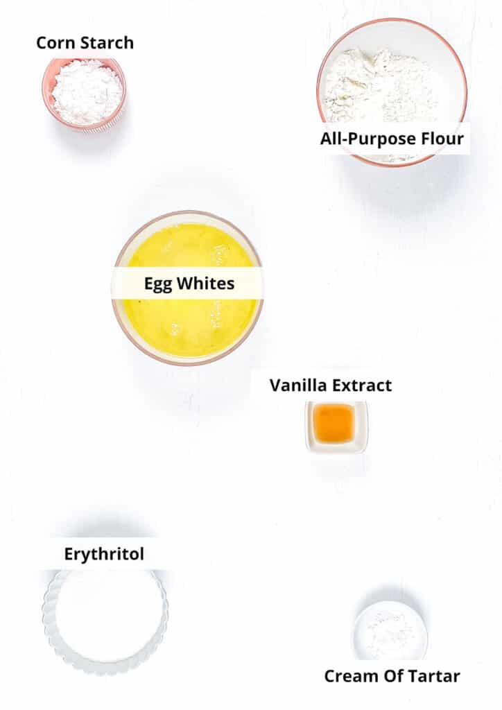 Ingredients for the sugar-free angel food cake are laid out in small ceramic dishes on a white background.